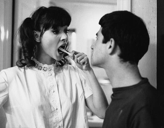 woman brushing teeth and man watching